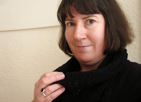 Woman holding a black knitted lacey scarf around her neck.