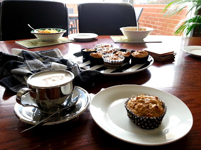 Plate of muffins on an office table, with bowls of lunch in the background.