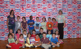 photo of: Kindergarten Children Pose in front of their Collaborative Quilt Project, for "Red, White and Blue" picture book by Debbie Clement