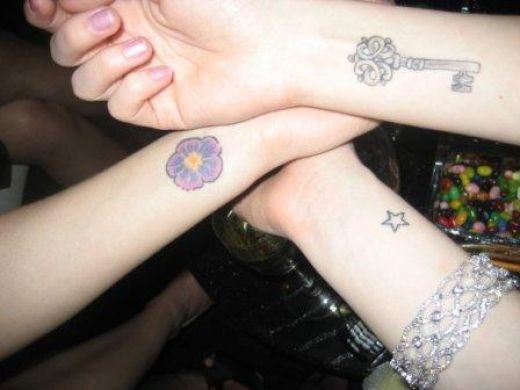 Three chicks comparing their wrist tattoos and my vote goes to the key 
