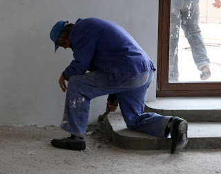Sally gets ready for tiling by smoothing out the floor Sally gets ready for tiling by smoothing out the floor
