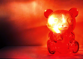 A miniature red plastic bear container. lit up from the inside.