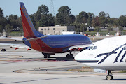 . into position for take off, while the Alaska Air plane waits patiently. (waiting )