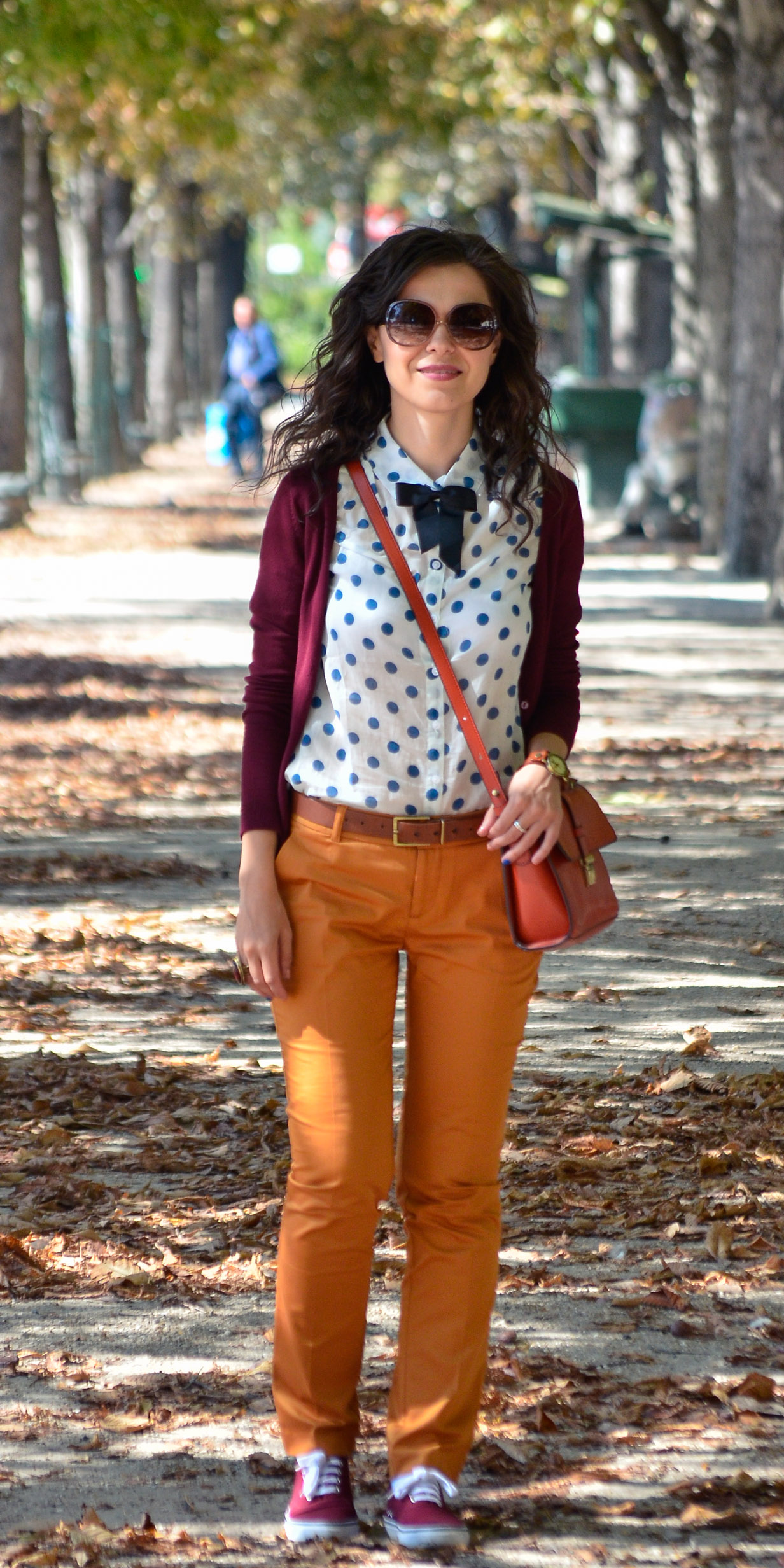 preppy fall outfit in Paris mustard pants burgundy sweater sneakers H&M orange satchel bag dotted shirt blue dots black bow tie champs elysees jardin de tuileries eiffel tower