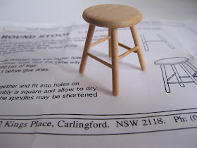 Wooden dolls' house miniature stool, sitting on the kit instruction sheet.