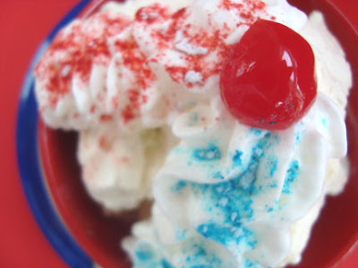 Sundae with cherry on top and two whipped cream lines one with red and one with blue sprinkles