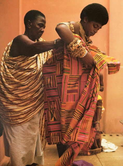 Queen mother being assisted to put on her Kente cloth as tradition and custom demands