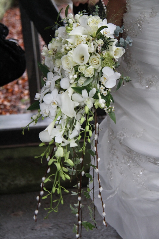 All white cascade wedding bouquet of Roses Orchids Lily of the Valley and