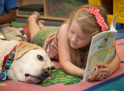 child reads to yellow Lab