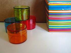 Four small coloured see-through miniature storage containers