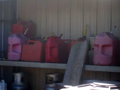 Pink and red plastic gas cans turned with their handles facing the camera, which makes them look like brooding, heavy-browed faces
