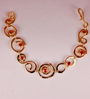 18k yellow gold bracelet with looping wire design and bezel set round orange sapphires