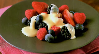Chilled summer berries served on a dessert place and drizzled with a white chocolate sauce