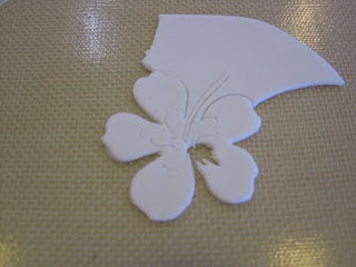 white fondant partially cut out in hibiscus form on baking mat