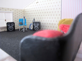 Interior of the first floor of a half-built Lundby dolls' house, with sofas and band equipment set up.