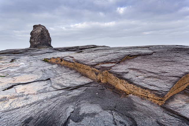 Saltwick Bay Black Nab with layers of rock in the foreground by Martyn Ferry Photography