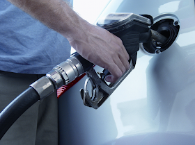 fuel pumped into a car by a man showing hand only