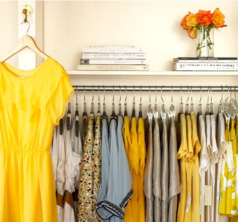 Closet with dresses and shirts in different shades of yellow, grey and taupe