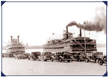 old black and photo of the belle of louisville at the warf with lots of trucks and cars from the 1940s pulled up along the warf