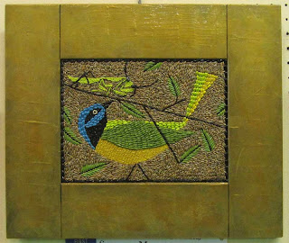 Colorful bird made from seeds with gold painted wooden frame