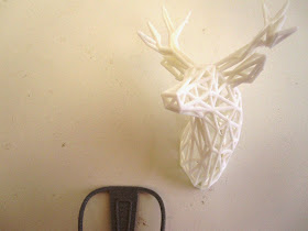 Modern dolls' house miniature 3D-printed cafe chair next to three 3D-printed stag head.