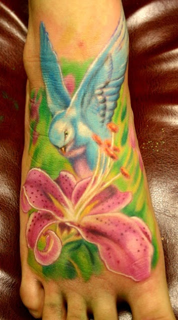 Kolorowy tatuaż ptaka i motywu kwiata na stopie