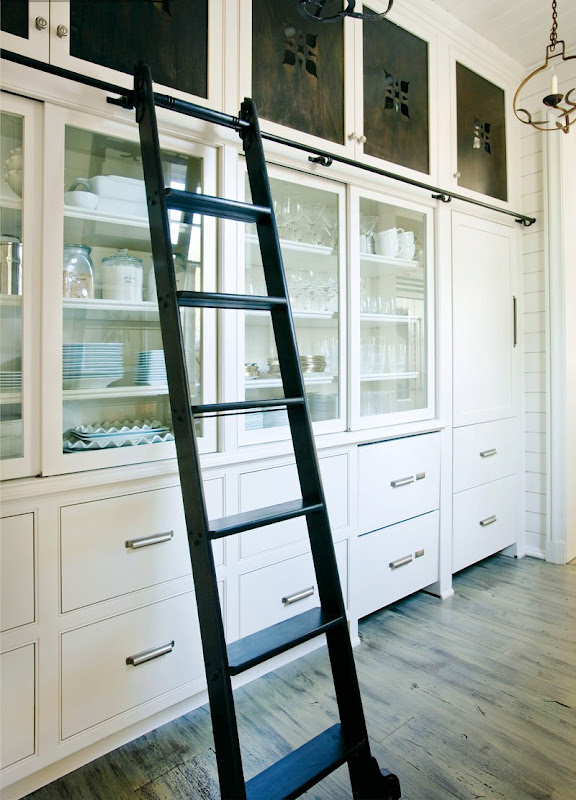 Organized white pantry with a black ladder on wheels to make reaching high cabinets easier