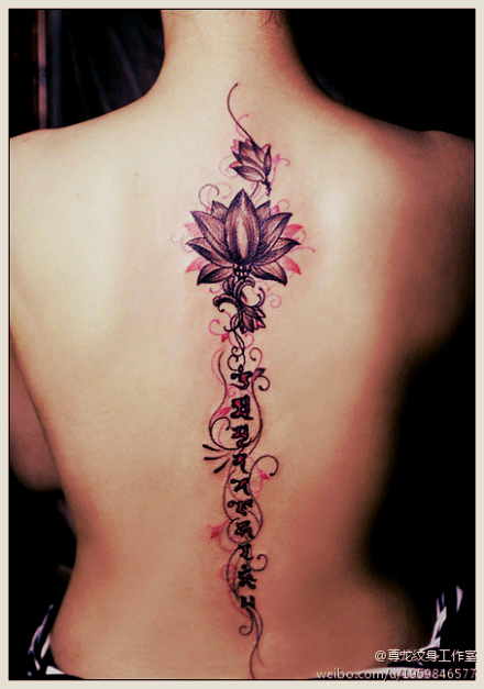 lotus flower and sanskrit tattoo along the spine