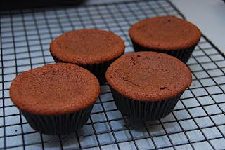 unfrosted dark chocolate cupcakes in dark wrapper cooling on rack