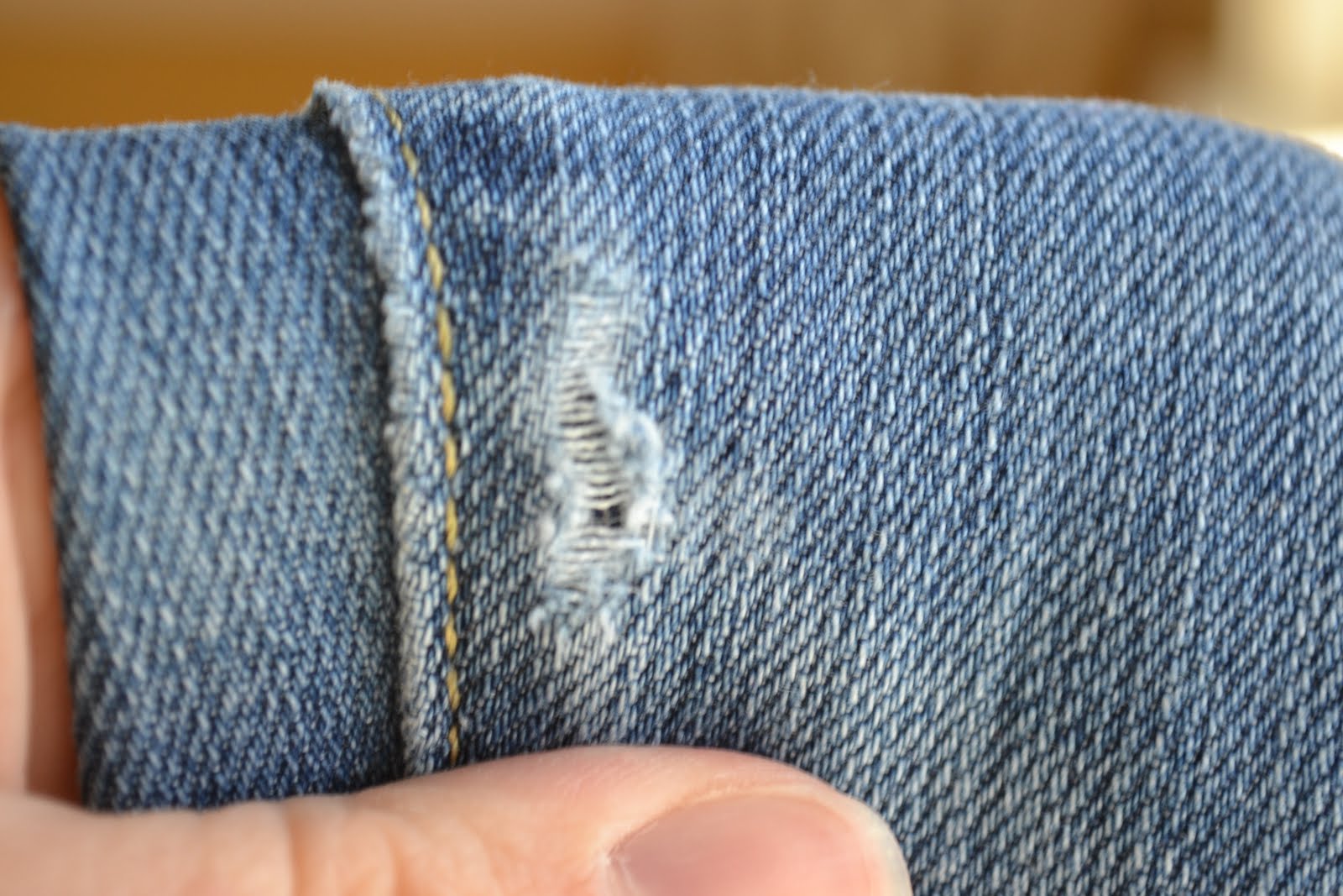 The hole on the seam with the mending tape on the inside of the jeans,
