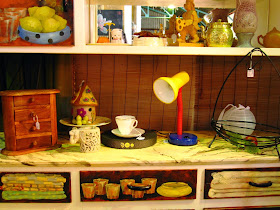 Vintage 1950s dresser, painted with trompe l'oeil of the contents of the cupboards and drawers. On it is displayed a number of items including a round house made of felt.