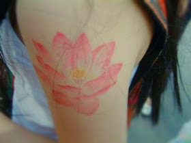 a light red lotus tattoo on the arm