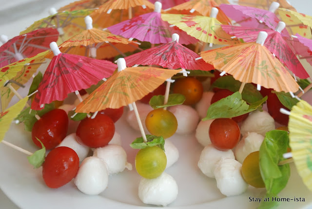 Skewering tomato mozzarella and basil onto cocktail umbrellas