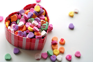colourful Valentine's Day heart shaped sweets being dispensed out of a heart shaped box