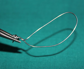 needle nosed pliers shaping a wire loop on a green background