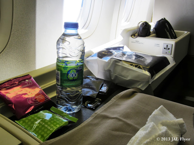 JAL First Class trip report on JL005 - Cabin attendants handed out bottled water and First Class amenity kits after first meal service