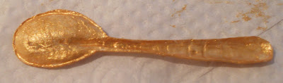 back view of a handmade paper golden spoon embossed with water