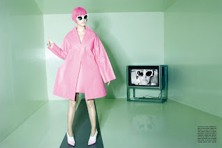 Katy Perry wearing a pink outfit with a TV in the background