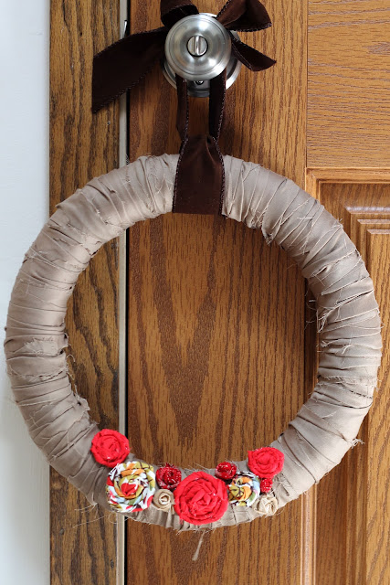 a brown wreath with red and white flowers hung on a doorknob