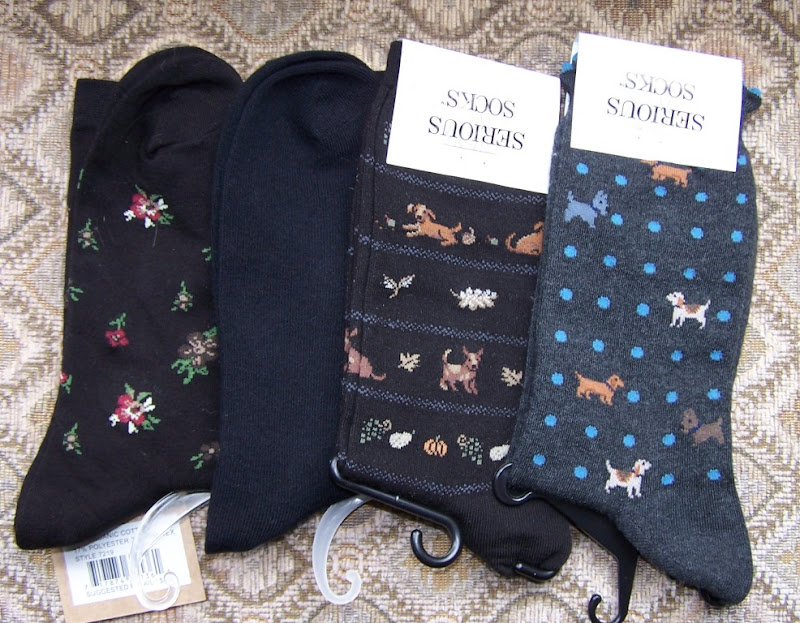 four pair of socks, one plain black, one with flowers, and two with adorable dogs woven in