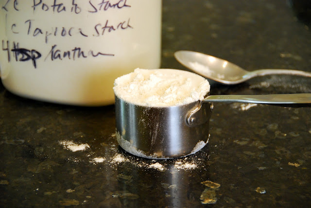 stainless steel measuring cup full of flour in front of flour container