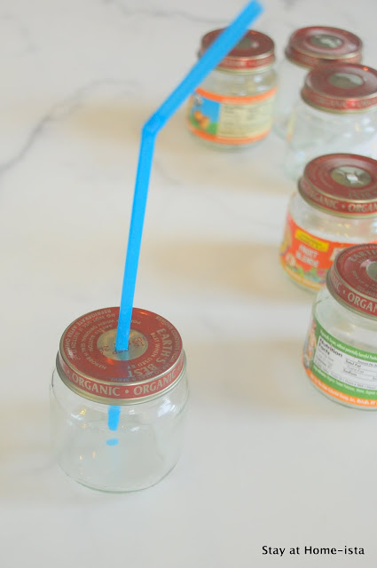 a straw through the lid of a baby food jar