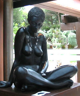 Statue en résine noire d'une femme nue assise en tailleur, tête baissée