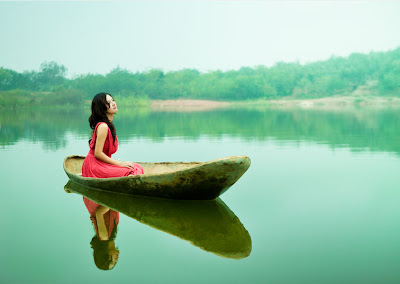Chica navegando en su balsa de madera por el lago de aguas tranquilas