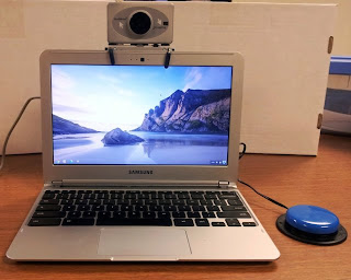 Photograph of the Chromebook open with the HeadMouse mounted to the top of the screen and the jellybean switch next to the computer.