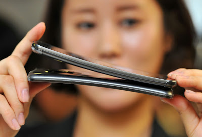 An official shows a Plastic OLED (POLED) display used in LG Electronics' curved-screen smartphone G Flex during a media event to unveil the new product at the company's headquarters in Seoul on November 5, 2013. The G Flex has a 6-inch plastic OLED display that curves inward from top and bottom. The device will hit the market in South Korea next week