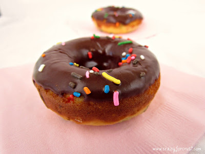 funfetti donuts with chocolate glaze and sprinkles on pink napkin