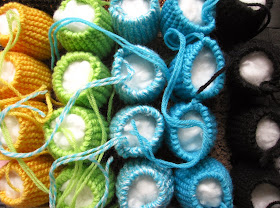 Rows of modern dolls' house miniature knitted pouffes, stuffed and awaiting sewing the tops.