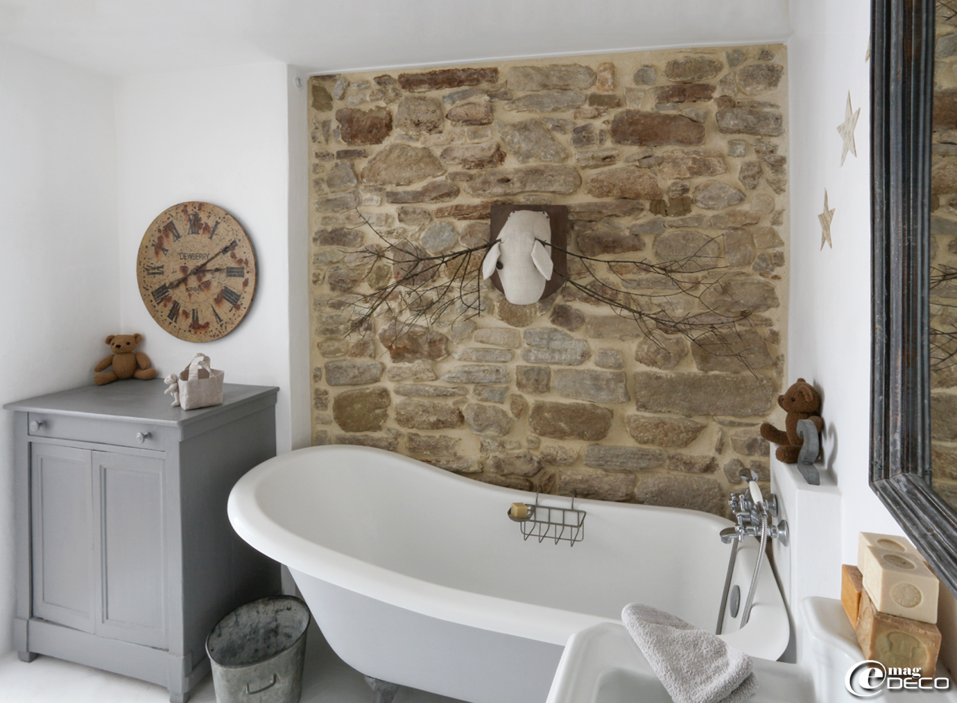 Dans une salle de bains, une vieux buffet peint en gris sert de rangement et de table à langer, horloge 'Country Corner'