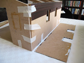 A half-built dolls' house shed, with weatherboard cladding fallen off the rear wall.